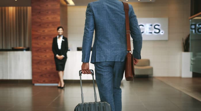 A business traveller walking through the lobby with a suitcase