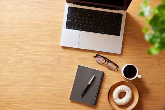 Laptop, notebook and coffee arranged on a wooden desk